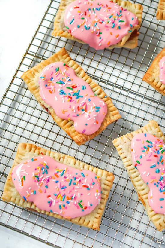 Homemade pop tarts recipe from Crimson tavernorlando x Alyssa Marie. Photo features pop tarts displayed don baking tray with pink frosting and colorful sprinkles. The pop tarts are gluten free and sugar free but look so yummy!